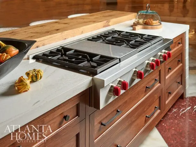 Wolf range with red knobs and wood cabinetry topped with white marble