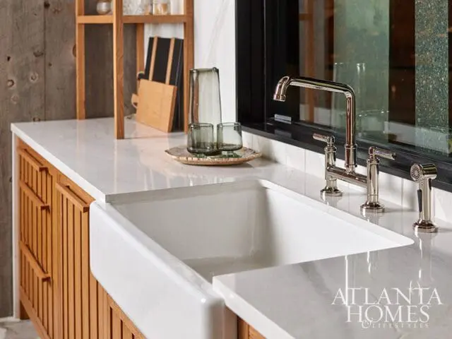 White farmhouse sink with chrome faucet and wooden cabinetry.