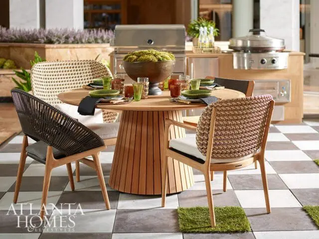 Round wood dining table with woven chairs and outdoor grill