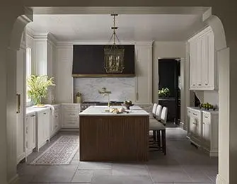 White kitchen with wood island, marble backsplash, brass accents, and pendant light
