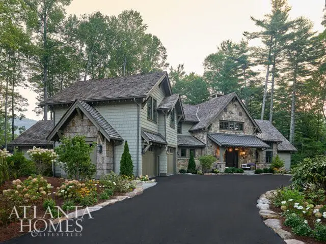 Stone and shingle house with a winding driveway and landscaped garden.