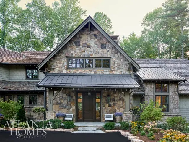 Stone and shingle house with metal roof and dark wood double doors.