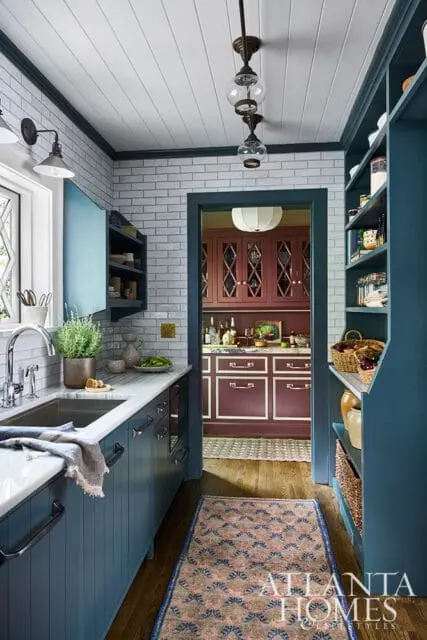 Blue kitchen cabinets with white subway tile backsplash and marble countertops.