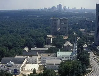 Aerial view of a city skyline with a church steeple and surrounding trees, buildings, and a highway.