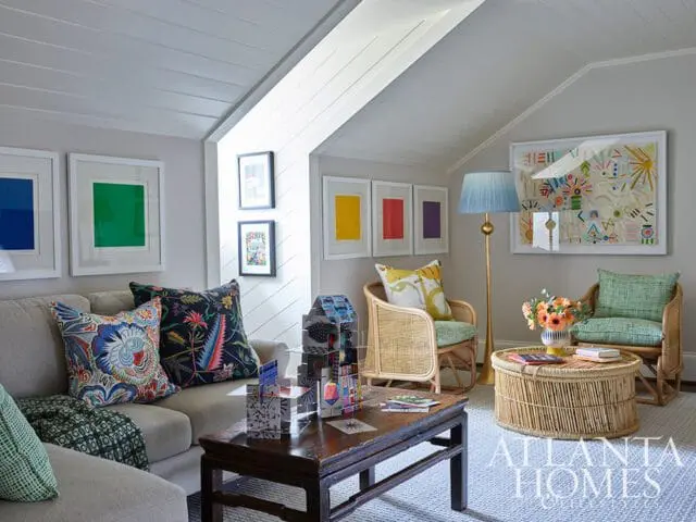 Living room with a sectional sofa, two rattan chairs, a wooden coffee table, and a round rattan coffee table. Artwork and colorful pillows add pops of color.