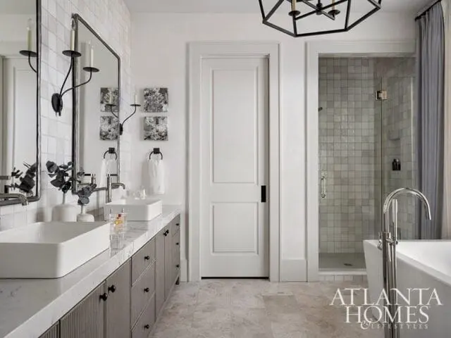 Modern bathroom with double vanity, white rectangular sinks, marble countertops, gray fluted cabinetry, and a glass-enclosed shower with gray tile.