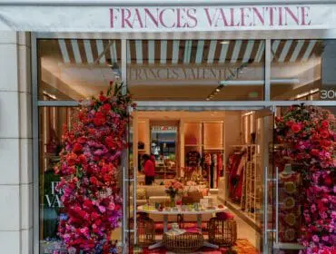 Frances Valentine storefront decorated with abundant red, pink, and purple floral arrangements flanking the entrance.