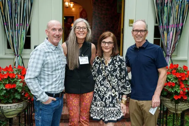 Four people posing outdoors at a garden party.