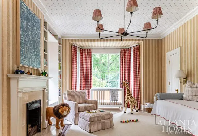 Children's room with striped wallpaper, a white crib, a stuffed lion, a giraffe toy, and a fireplace with a marble surround.