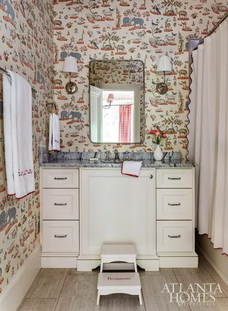 Cream bathroom vanity with marble countertop, animal print wallpaper, and a step stool labeled 'Benjamin'.