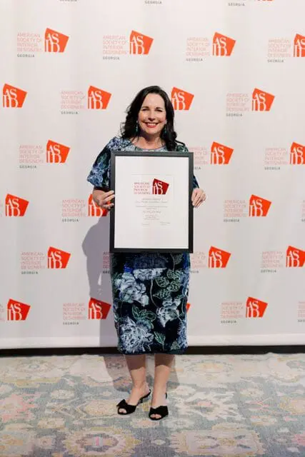 Woman in floral dress holding an award from the American Society of Interior Designers Georgia Chapter