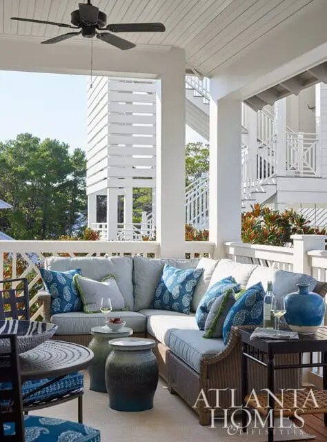 Covered porch with sectional sofa, blue paisley pillows, wicker furniture, and a ceiling fan.
