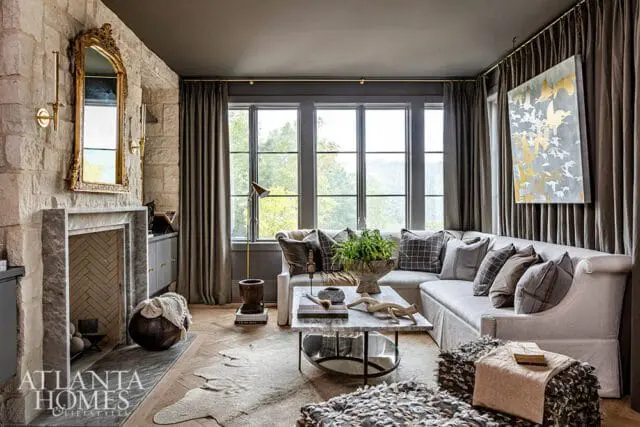Living room with stone fireplace, sectional sofa, marble coffee table, and artwork of birds on the wall.