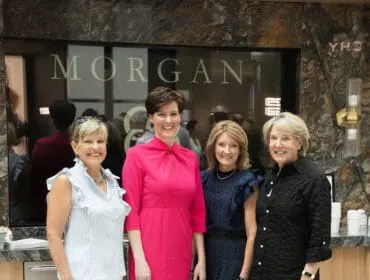 Four women pose in front of a wall with the word "MORGAN" visible in large letters.
