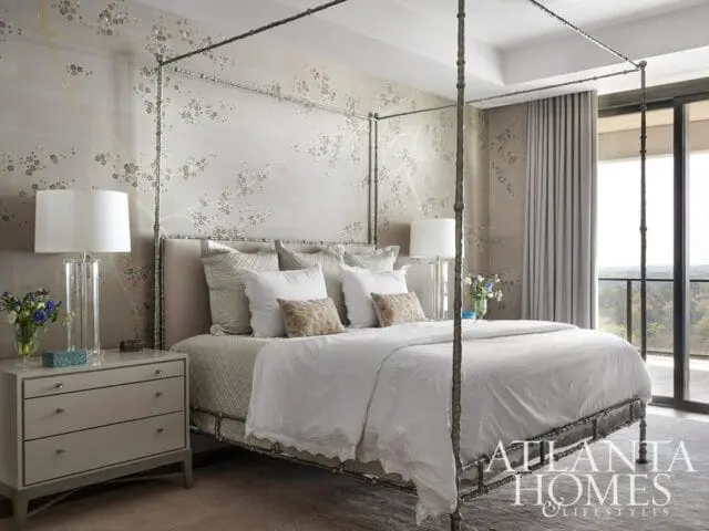Bedroom with a four-poster bed, textured wallpaper featuring a floral branch motif, and a gray dresser with glass lamps.