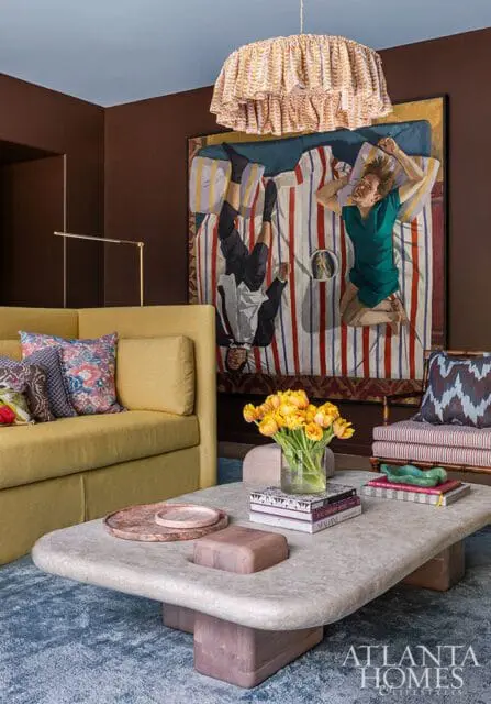 Living room with a yellow sofa, abstract art, and a stone coffee table with yellow tulips.
