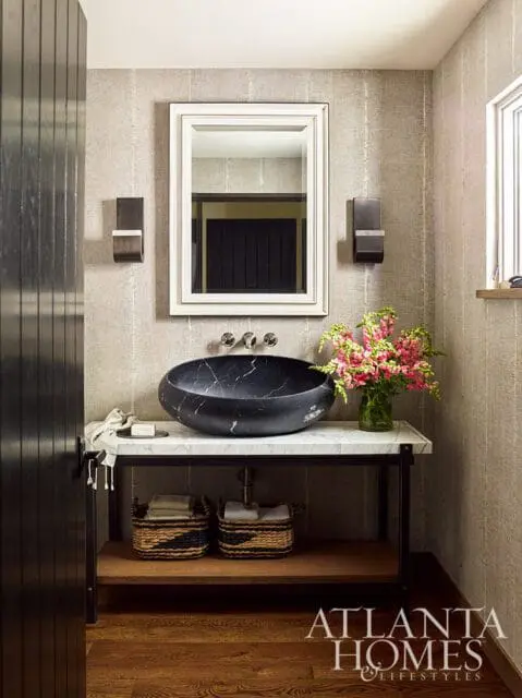 Powder room with textured wallpaper, black marble vessel sink on a white marble vanity, and dark wood accents.
