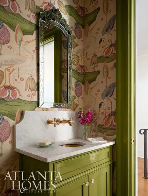 Powder room with a vibrant botanical wallpaper, a green vanity with marble countertop, brass faucet, and an ornate mirror.