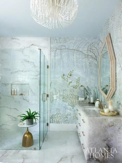 Light blue bathroom with marble shower and vanity, botanical wallpaper, and a white chandelier.