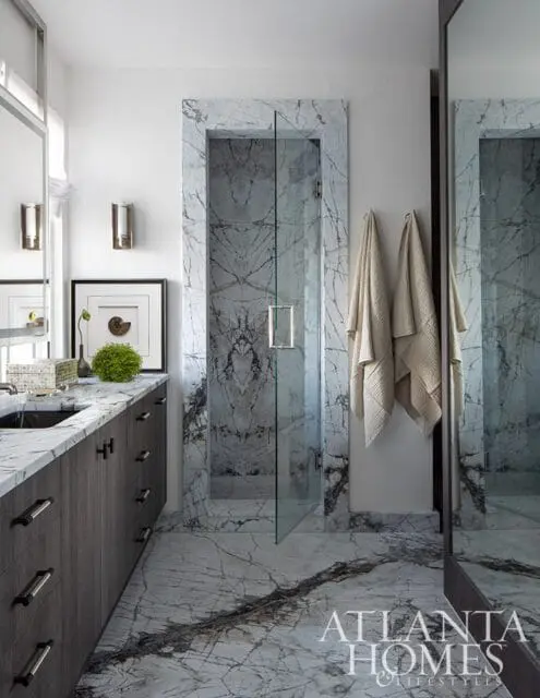 Modern bathroom with dark wood vanity, white marble countertops, and a glass-enclosed shower with marble tile surround and flooring.
