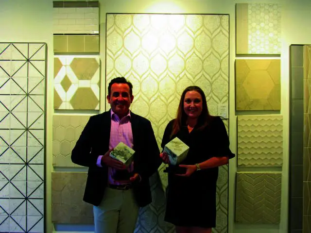 Man and woman holding awards in front of tile samples.