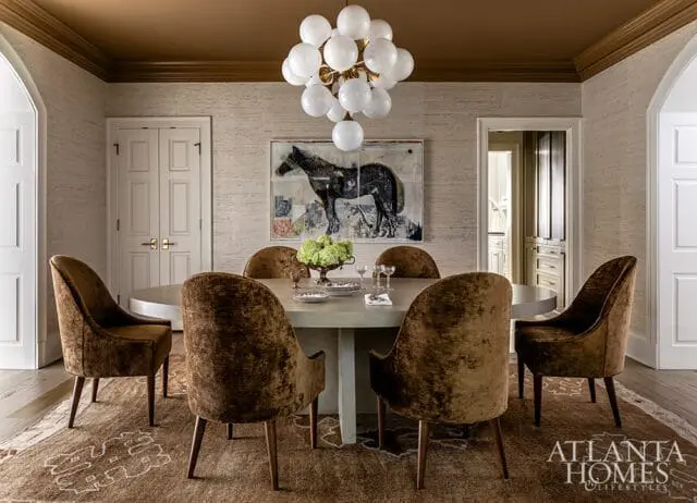 Dining room with oval table, velvet chairs, horse artwork, and globe chandelier.