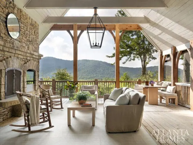 Covered porch with stone fireplace, rocking chairs, sofa, and mountain view
