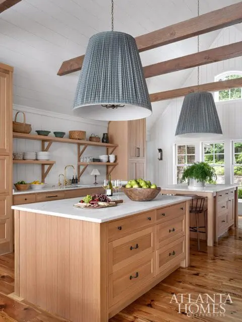 Wood kitchen with marble countertops, two islands, and large pleated pendant lights