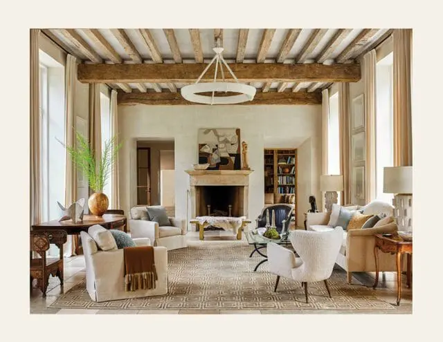 Living room with exposed wooden beams, stone fireplace, and neutral-toned furniture.