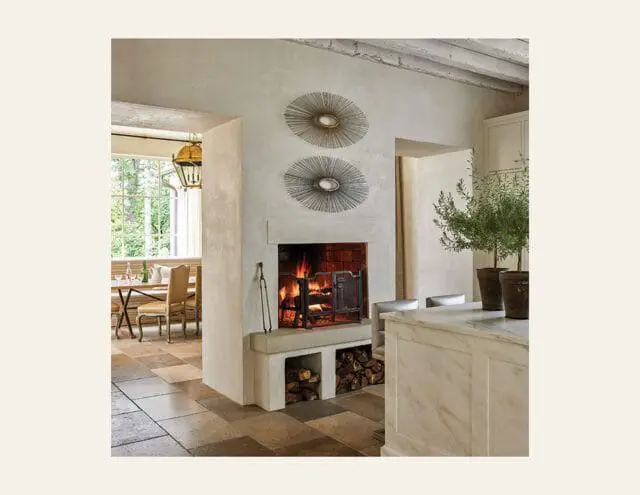 Living room with fireplace, stone floor, and dining area visible through doorway.