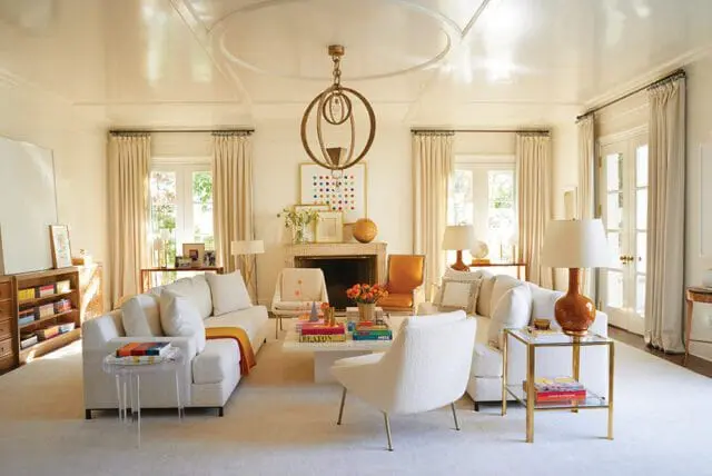 Living room with white sofas, fireplace, colorful artwork, and ornate chandelier.