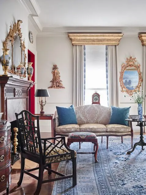 Living room with ornate fireplace, patterned sofa, and dark wood chair.