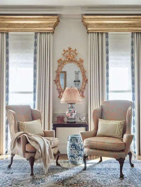 Two wingback chairs in a living room with patterned upholstery, ornate mirror, and blue and white
