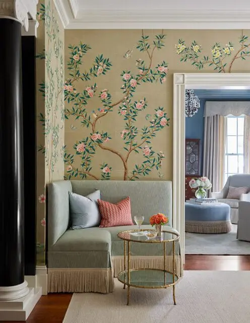 Pale green sectional sofa with fringe trim and patterned pillows, next to a gold bamboo table with