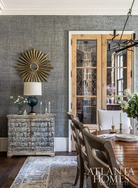 Dining room with blue patterned cabinet, sunburst mirror, and wine cellar doors