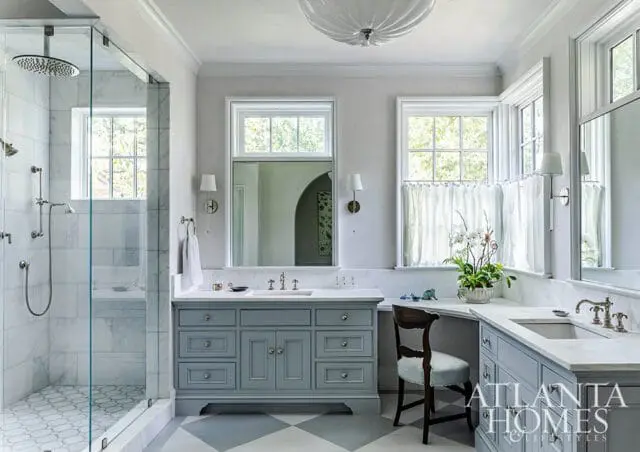 Gray vanity with marble countertop, glass shower with marble tile, and diamond pattern floor.