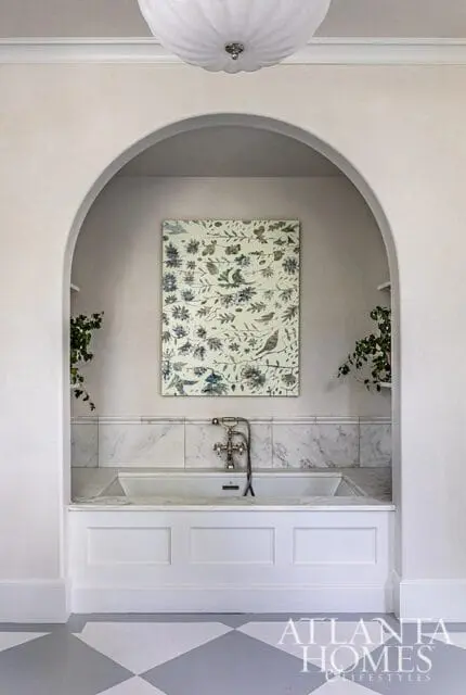 Bathroom with arched alcove, marble tub surround, floral artwork, and Atlanta Homes & Lifestyles