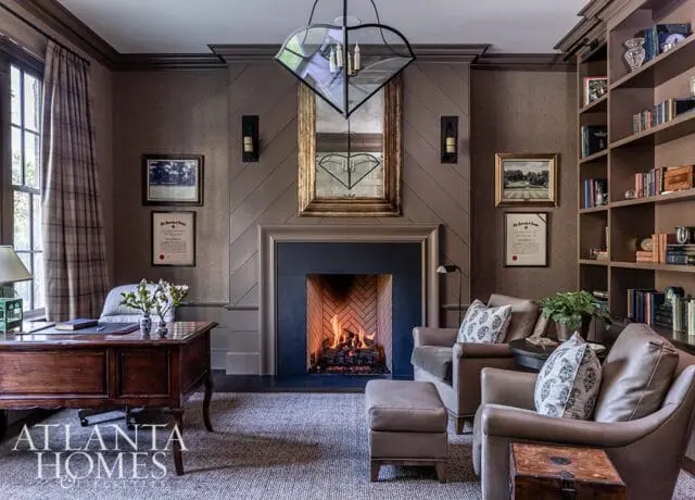 Office with fireplace, leather chairs, wooden desk, and bookshelves.