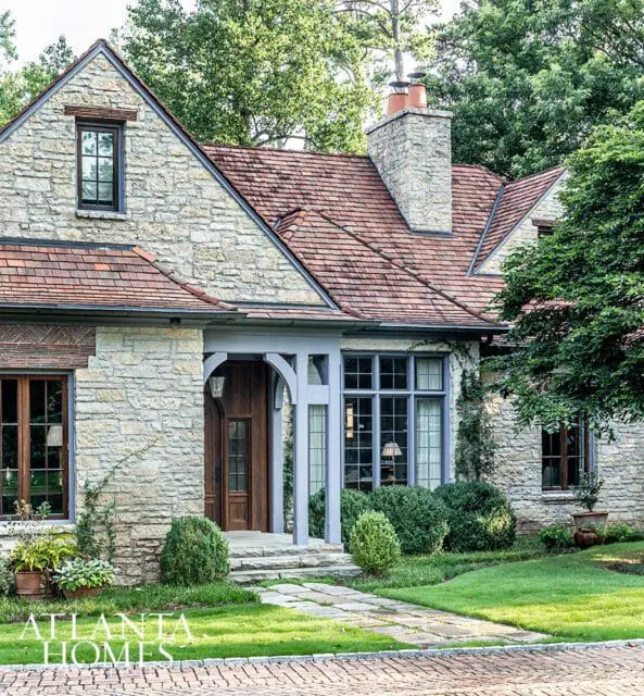 Stone house with red tile roof, arched entryway, and large windows.
