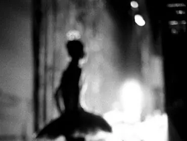 Black and white abstract image of a ballerina in a tutu, with blurred background.