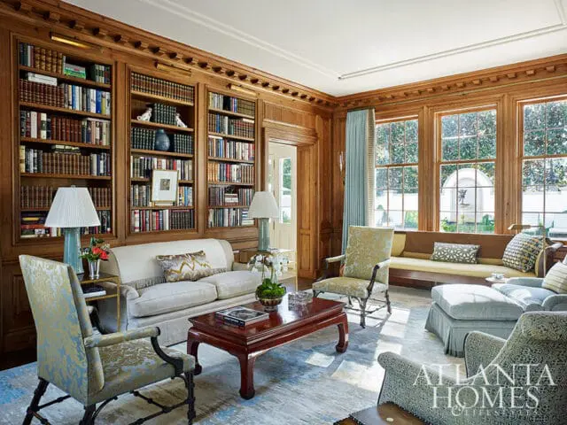 Living room with floor-to-ceiling bookshelves, upholstered furniture, and a dark wood coffee table.