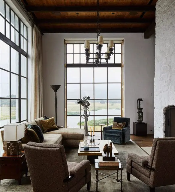 Living room with sectional sofa, two armchairs, and large windows overlooking a lake.