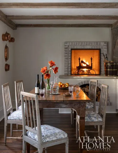 Dining room with rustic wooden table, chairs with floral cushions, and fireplace