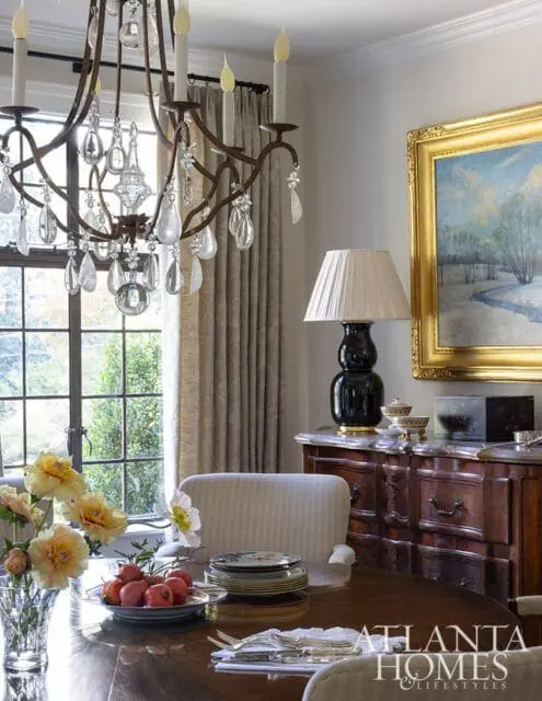 Dining room with crystal chandelier, wooden table, and antique buffet.