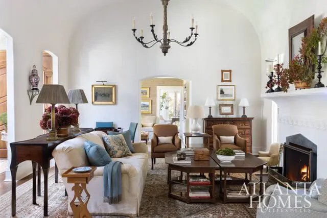 Living room with cream sofa, brown armchairs, dark wood tables, and fireplace.