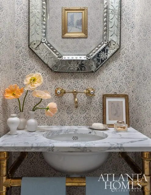 Powder room with marble vanity, ornate mirror, and floral wallpaper.