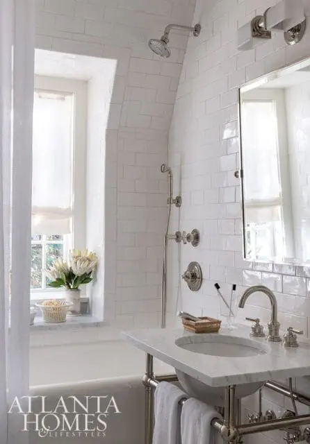 White subway tile bathroom with marble vanity, chrome fixtures, and arched shower
