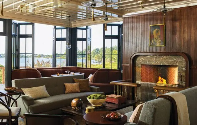Living room with gray sofa, brown sectional, fireplace, and large windows overlooking water