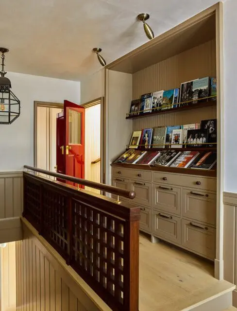 Hallway with red door, dark wood railing, and built-in shelves with magazines