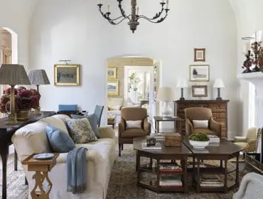 Living room with cream sofa, brown armchairs, dark wood furniture, and fireplace.